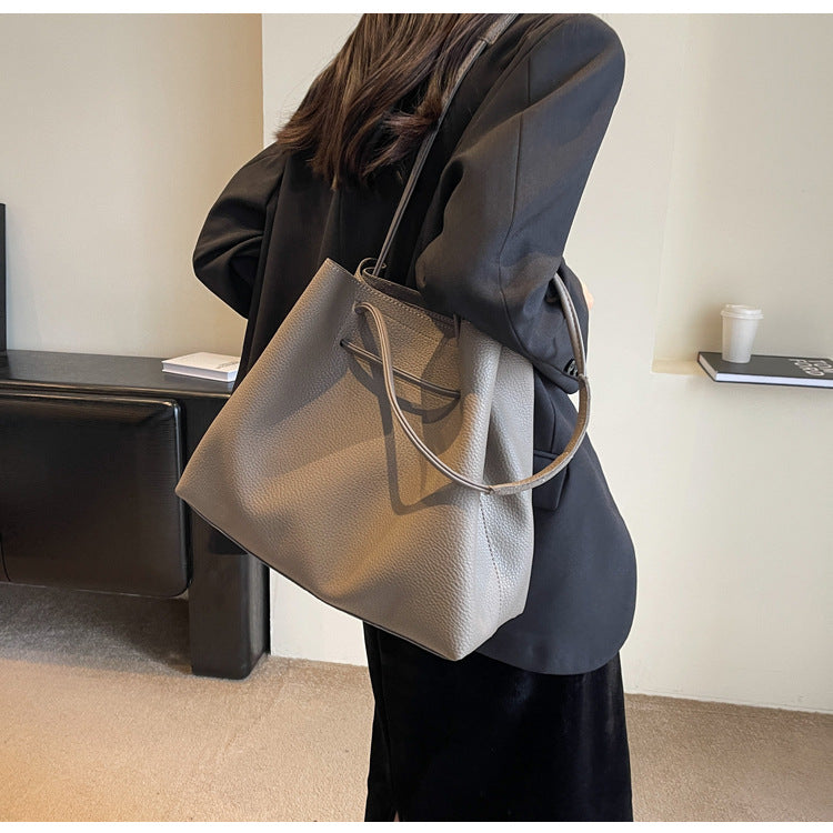 Person holding a gray handbag in an indoor setting