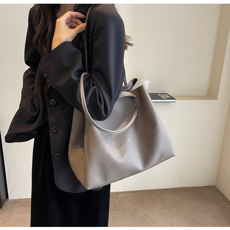 Person holding a gray handbag with a neutral background