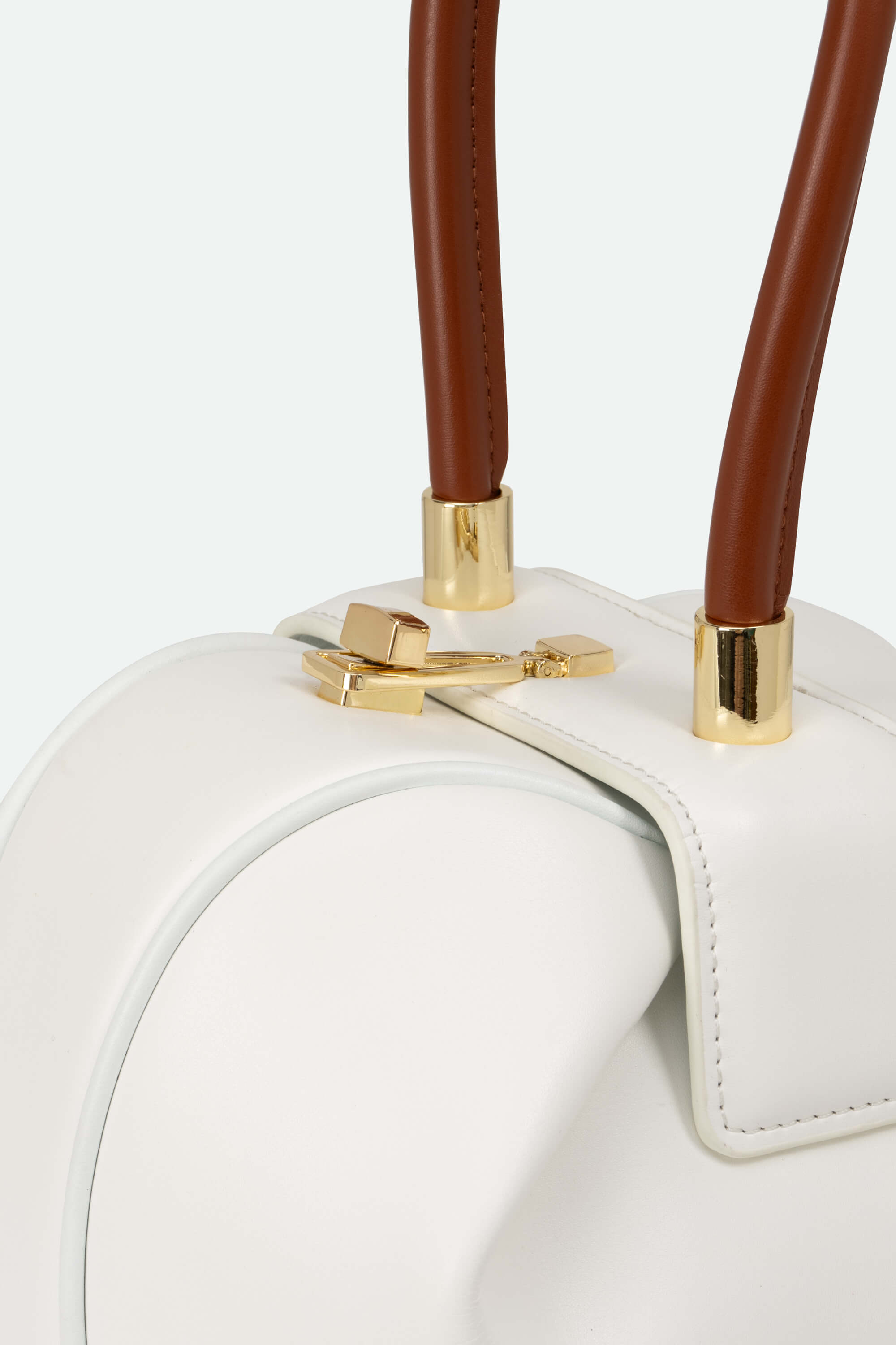 White handbag with brown handles and gold accents on a light gray background