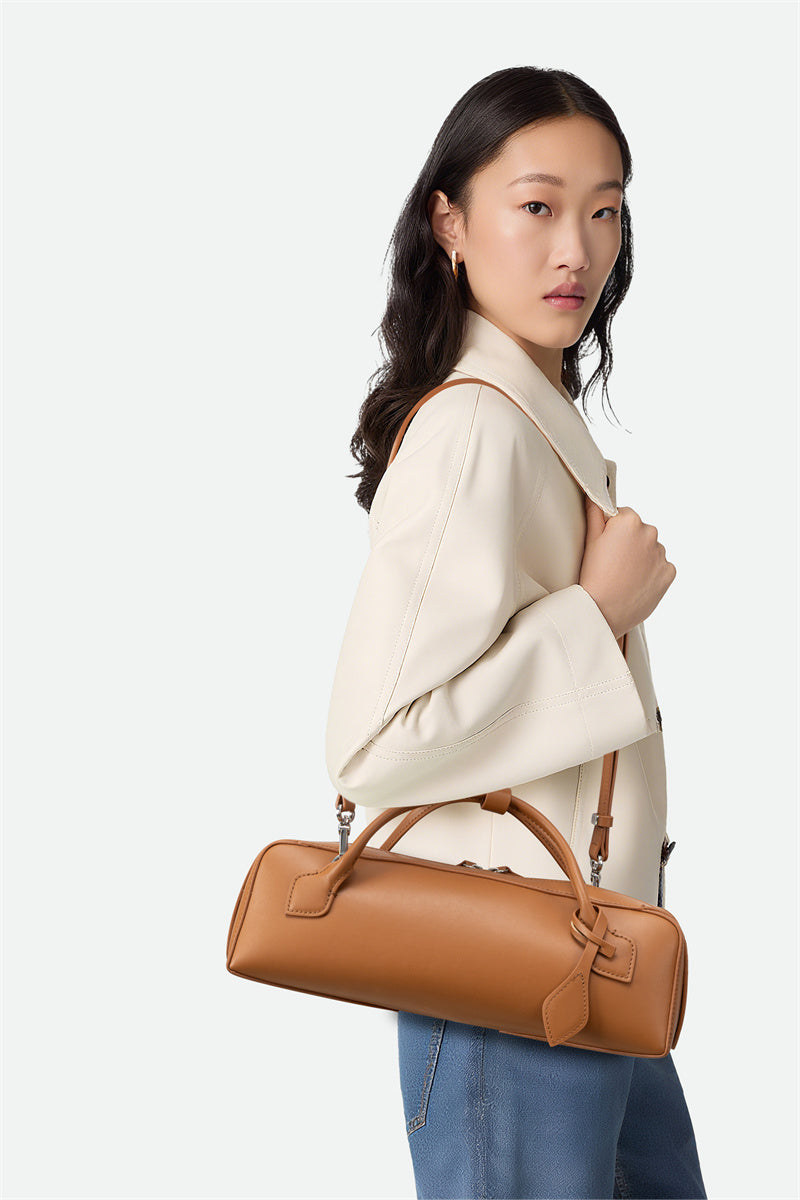 Woman holding a brown leather handbag against a white background