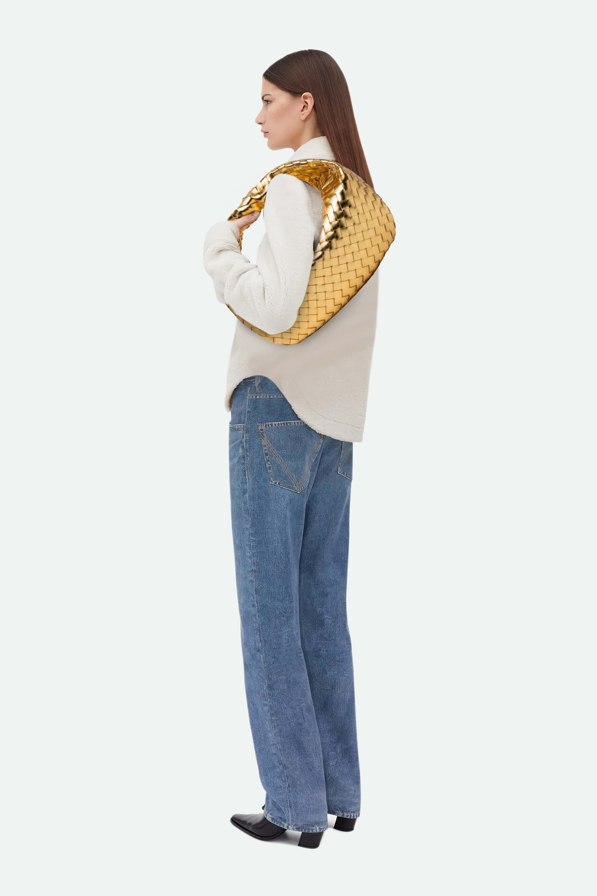 Woman wearing a gold quilted jacket and blue jeans on a white background