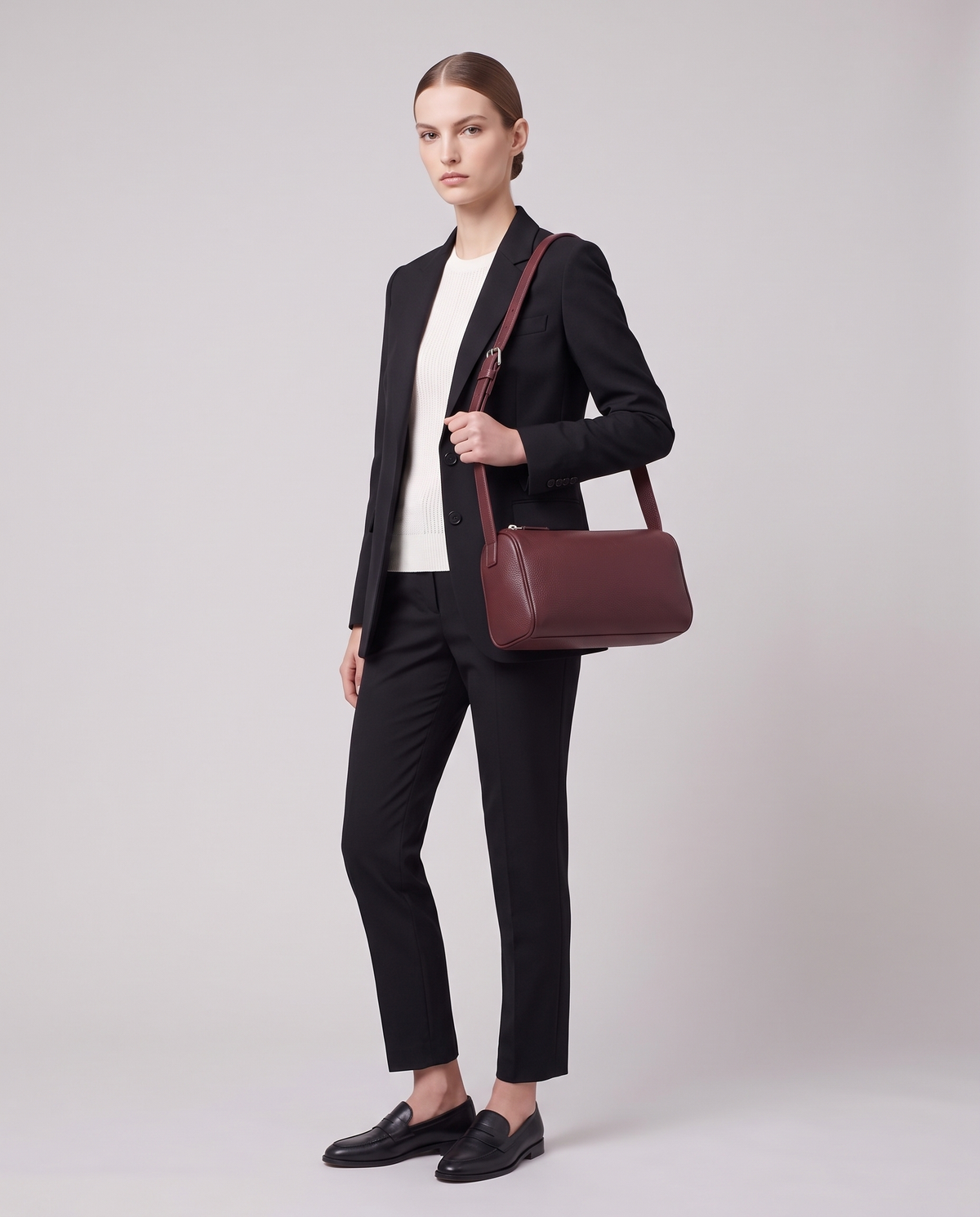 Model carrying the Alba barrel shoulder bag in Burgundy leather on the shoulder