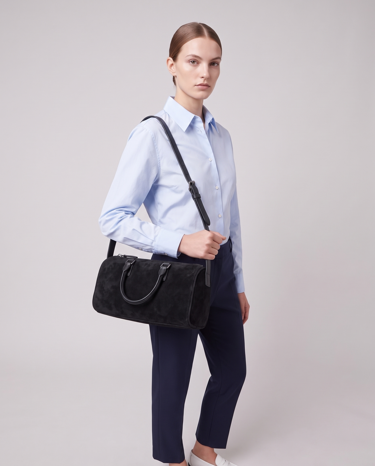 Model carrying the Alba barrel shoulder bag in Onyx black suede on the shoulder
