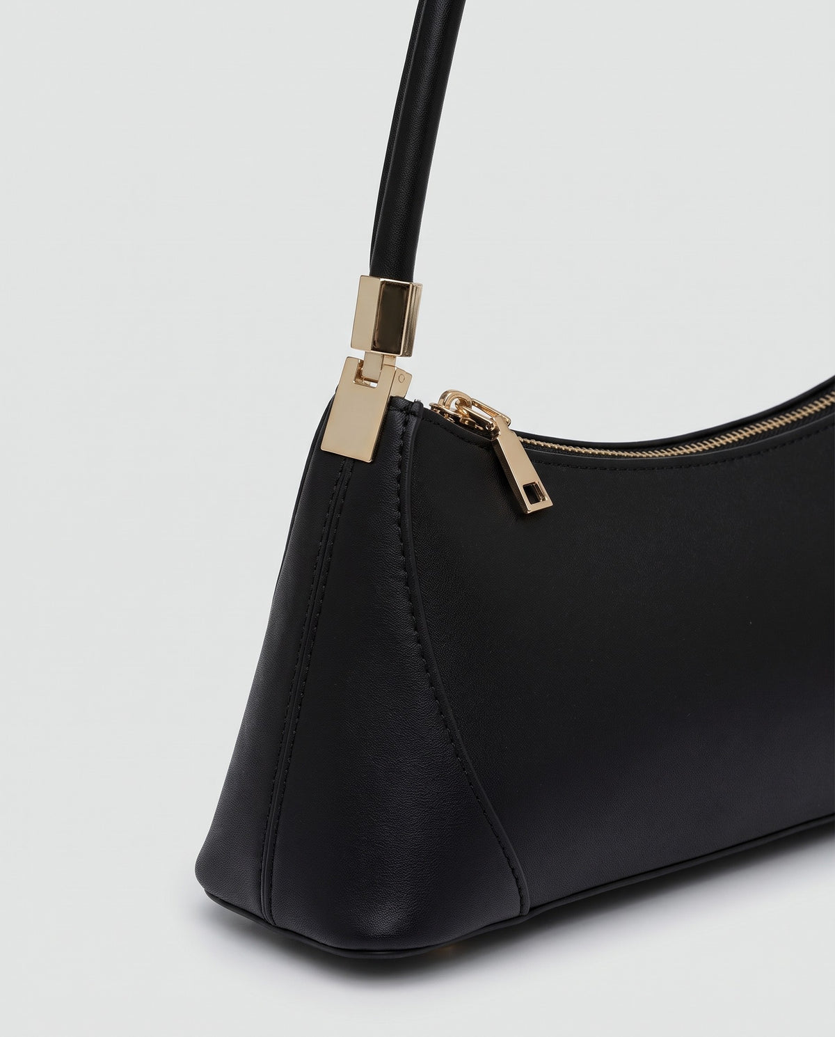 Arc leather shoulder bag in Black – close-up of the gold strap fitting and zip pull