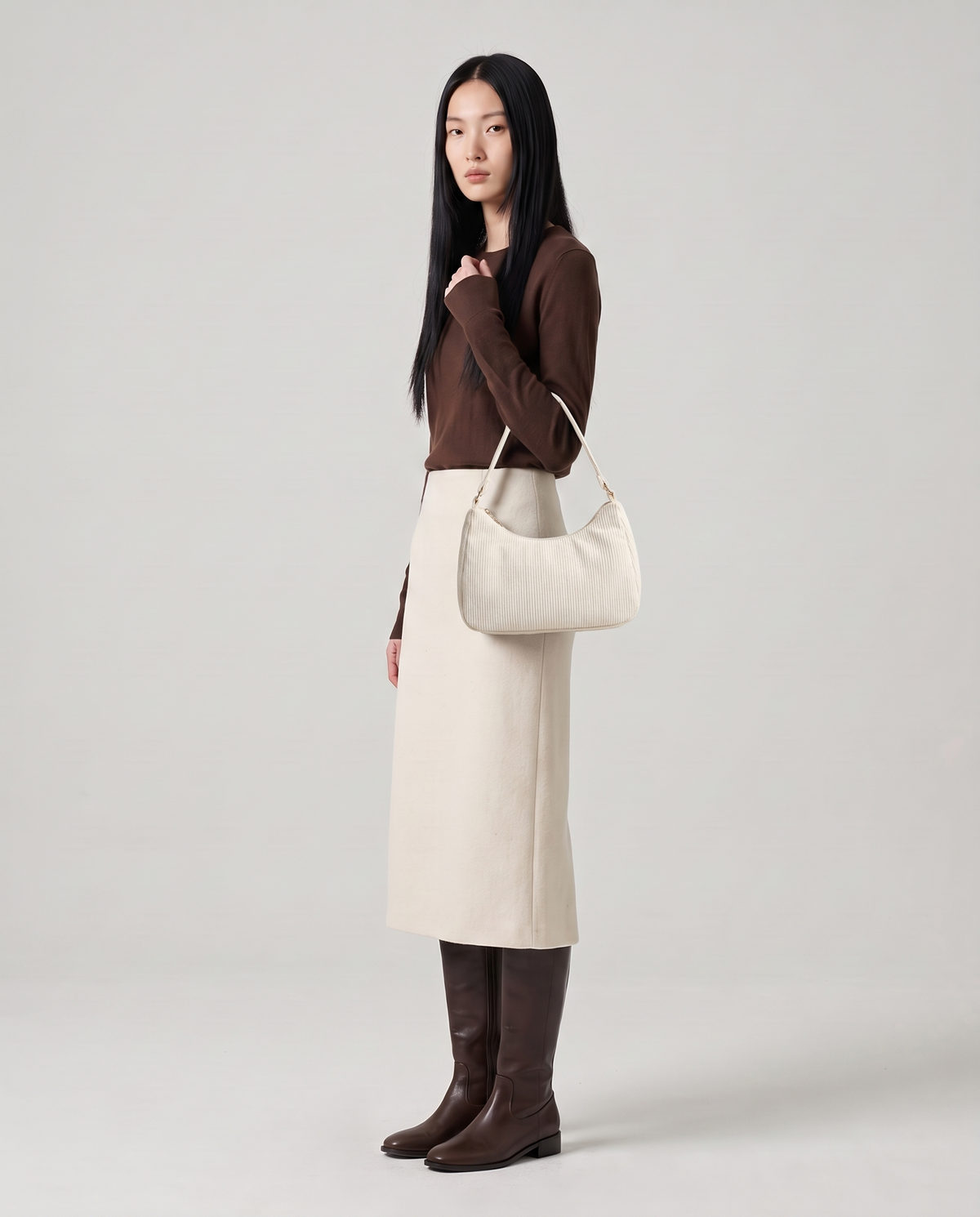 Aura corduroy shoulder bag in White – model wearing it on her shoulder, full length