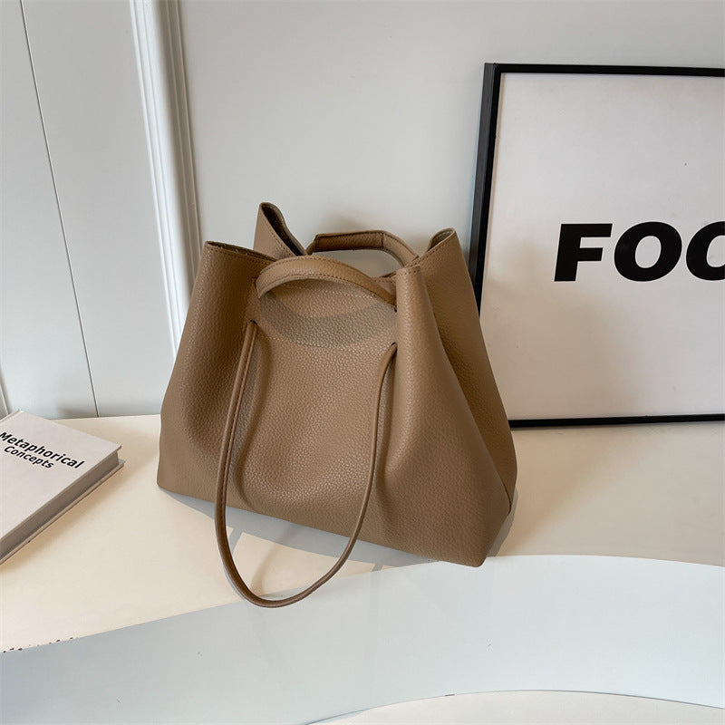Beige leather tote bag on a white surface with a black frame in the background