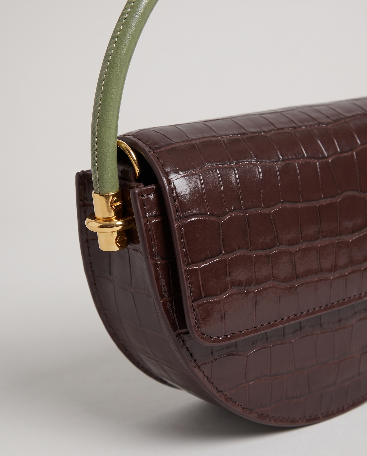 Crescent croc-embossed half-moon bag in Brown – close-up of the croc texture and gold handle fitting