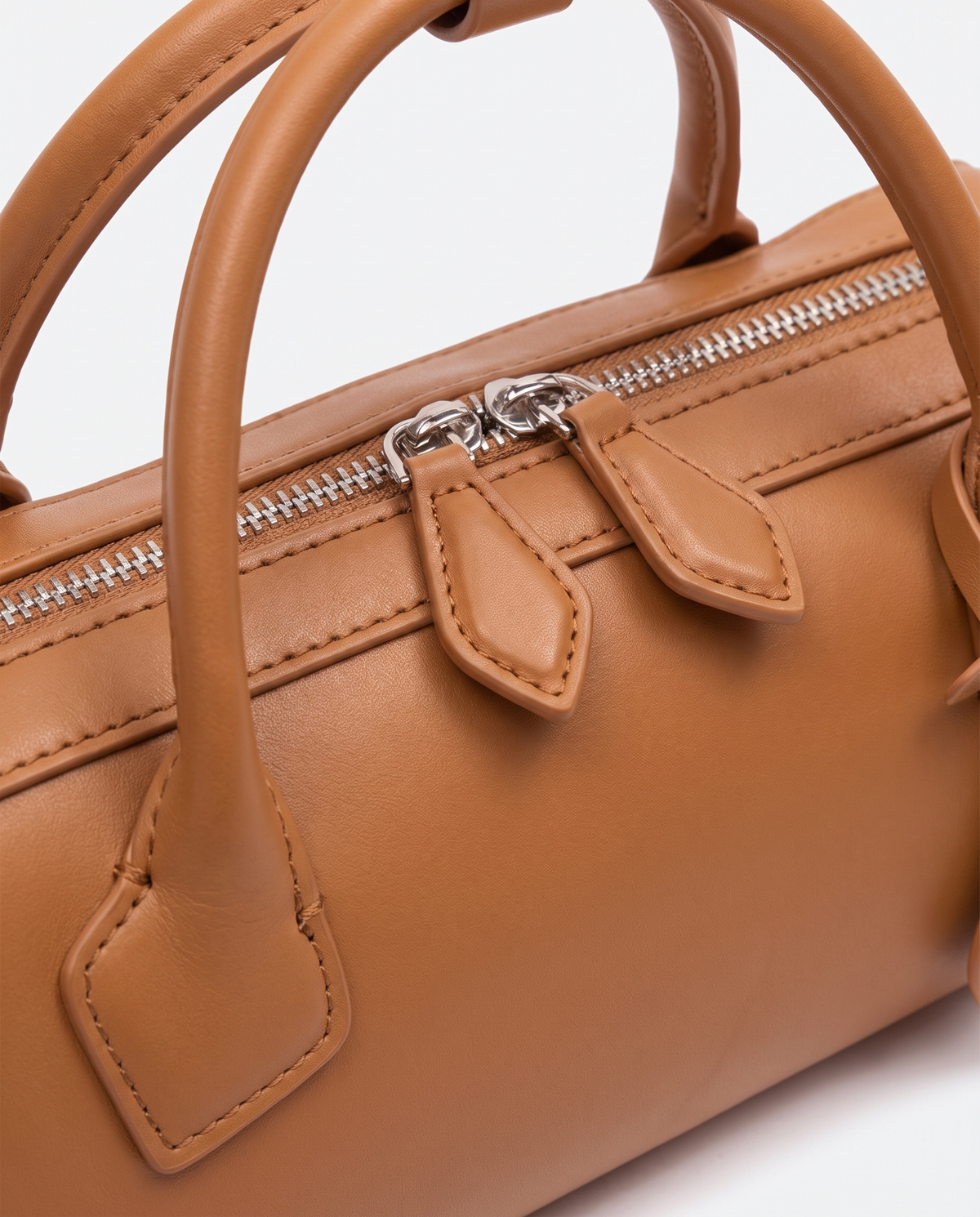 Curve leather barrel bag in Caramel – close-up of the handle and zip pulls