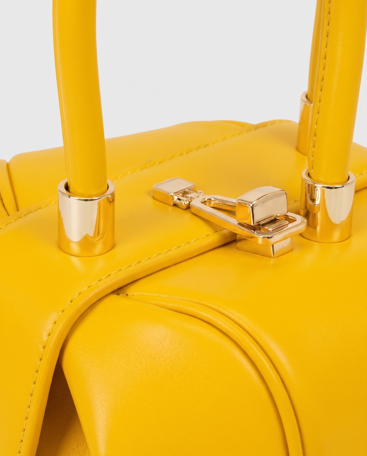 Dumpling Maxi leather top-handle bag in Yellow – close-up of the gold twist-lock and handle fittings