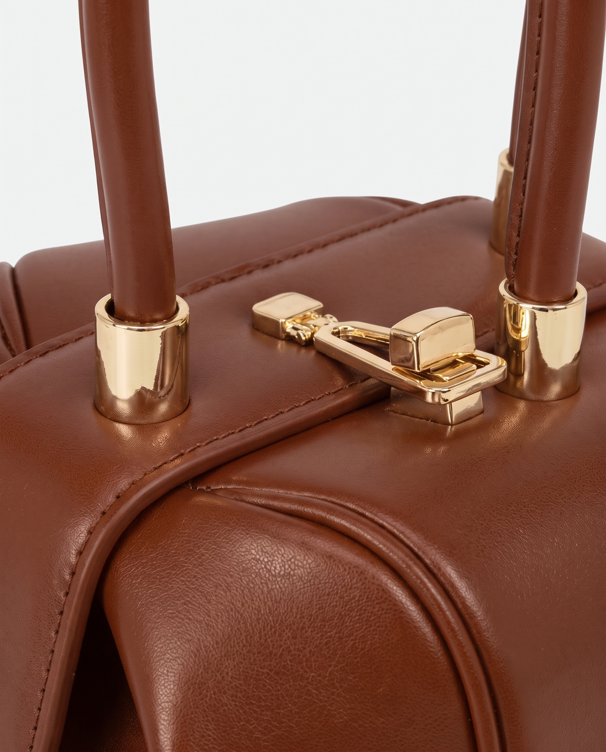 Dumpling Mini leather top-handle bag in Brown – close-up of the gold twist-lock and handle fittings