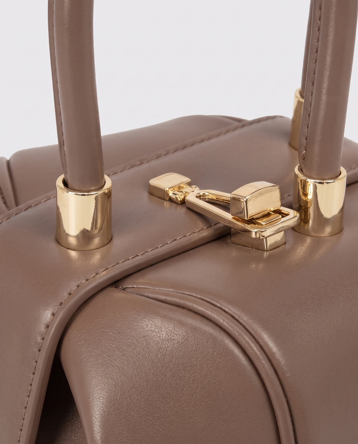 Dumpling Mini leather top-handle bag in Nude – close-up of the gold twist-lock and handle fittings