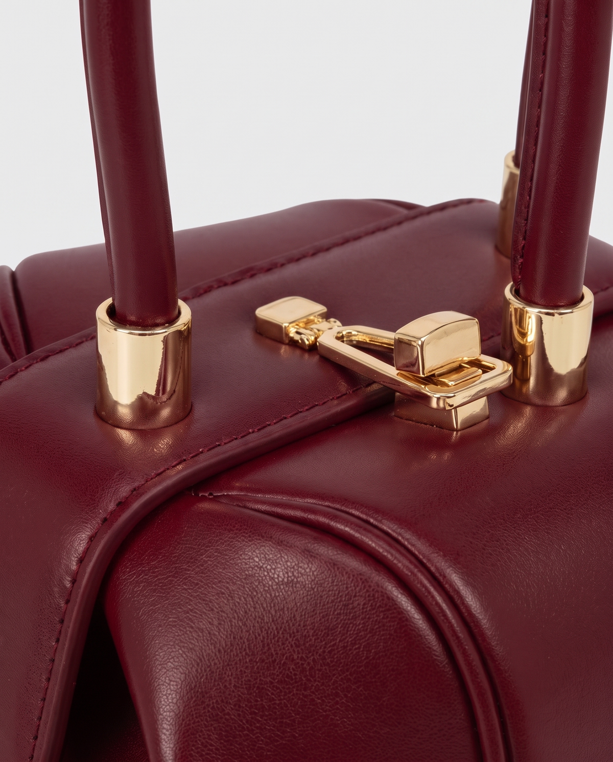 Dumpling Mini leather top-handle bag in Red – close-up of the gold twist-lock and handle fittings
