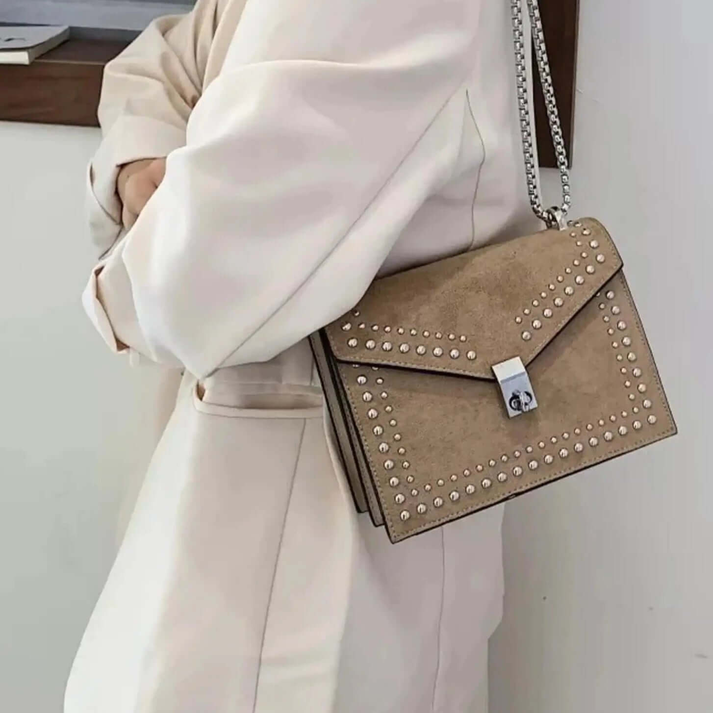 A girl carrying a beige studded vegan leather bag