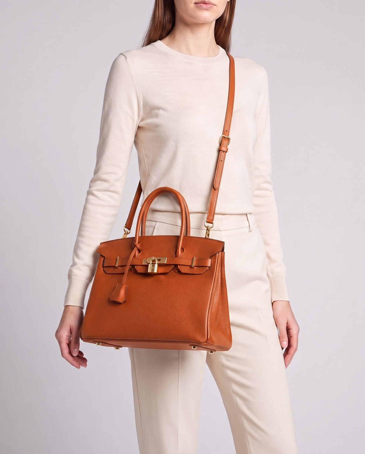 Lock Medium leather top-handle bag in Terracotta – model wearing it crossbody on the detachable shoulder strap