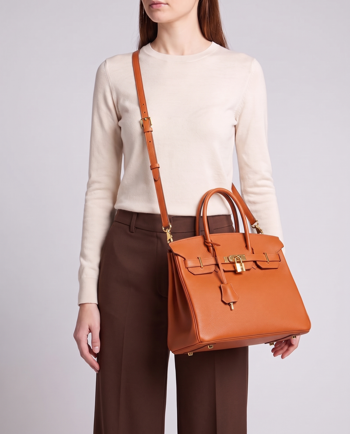 Lock Medium leather top-handle bag in Terracotta – model wearing it crossbody on the detachable shoulder strap