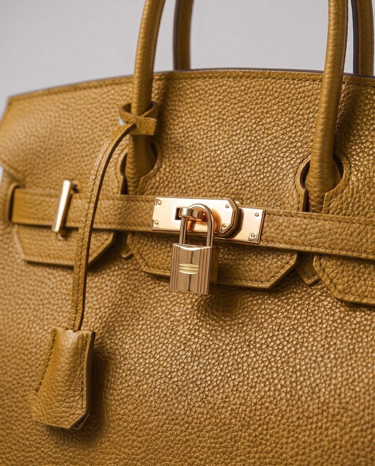 Lock Small leather top-handle bag in Mustard – close-up of the gold turn-lock and padlock