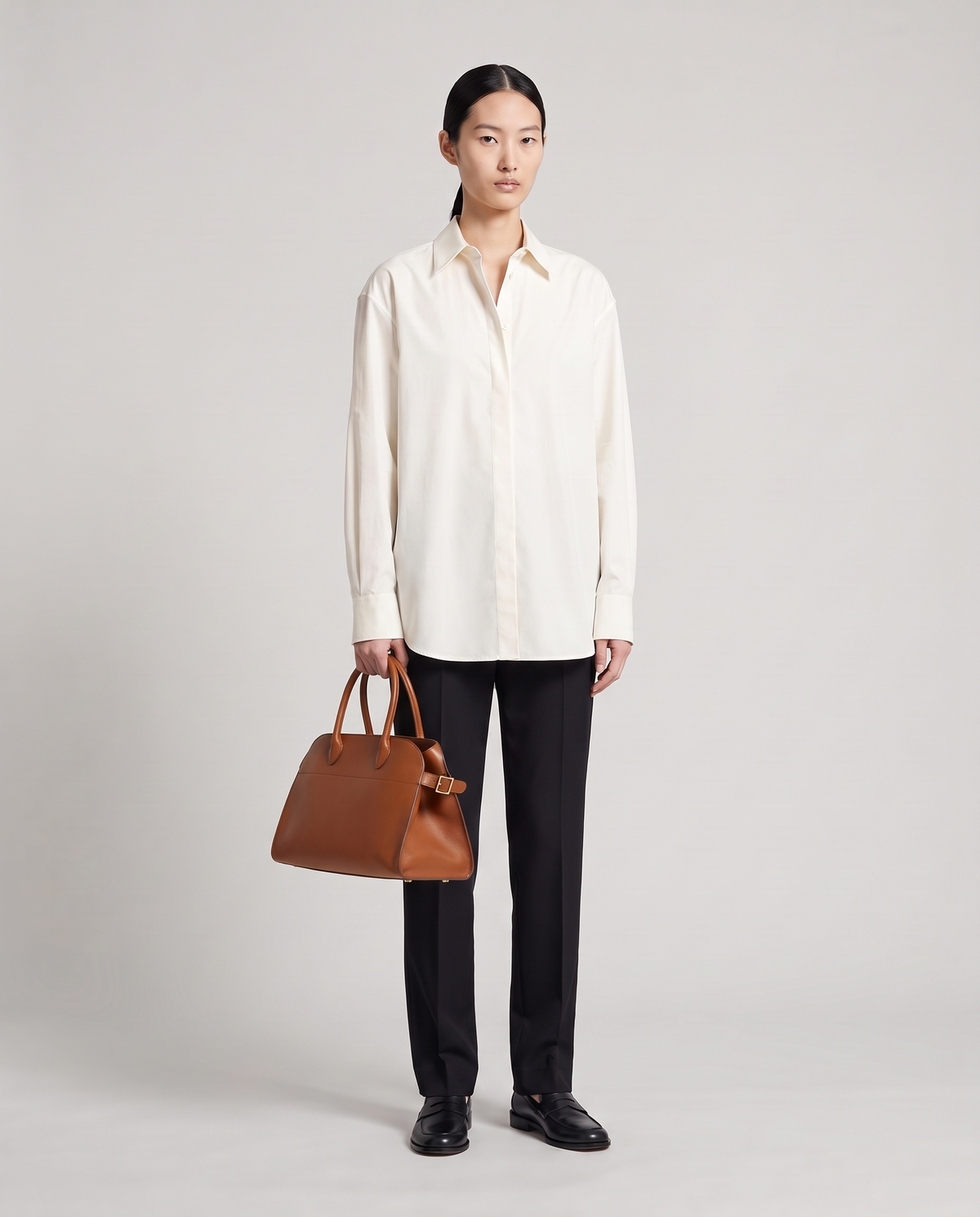 Milano Small top-handle bag in Brown – model holding it by the top handles, full length