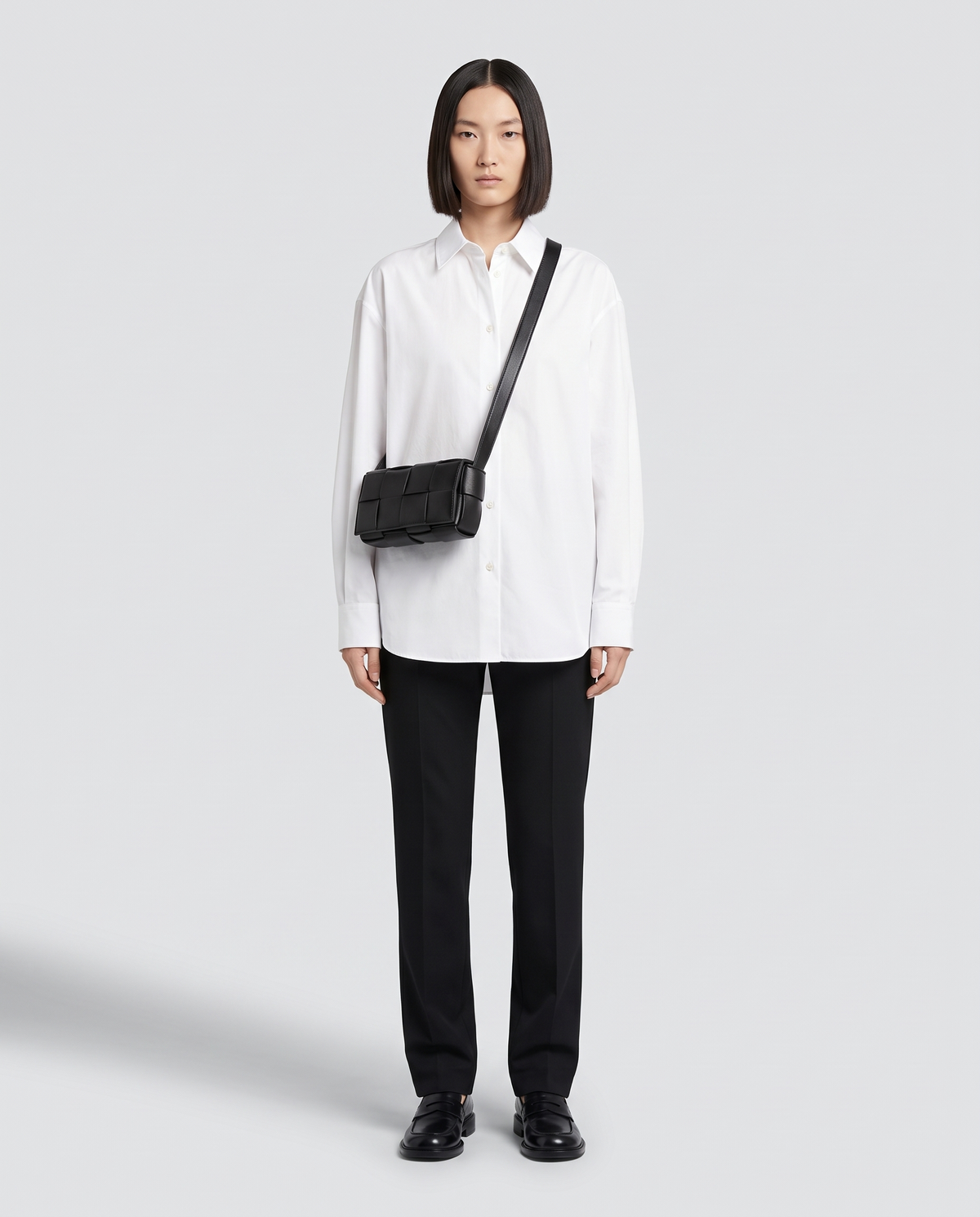 Cassette padded woven leather belt bag in Black – model wearing it crossbody, full length