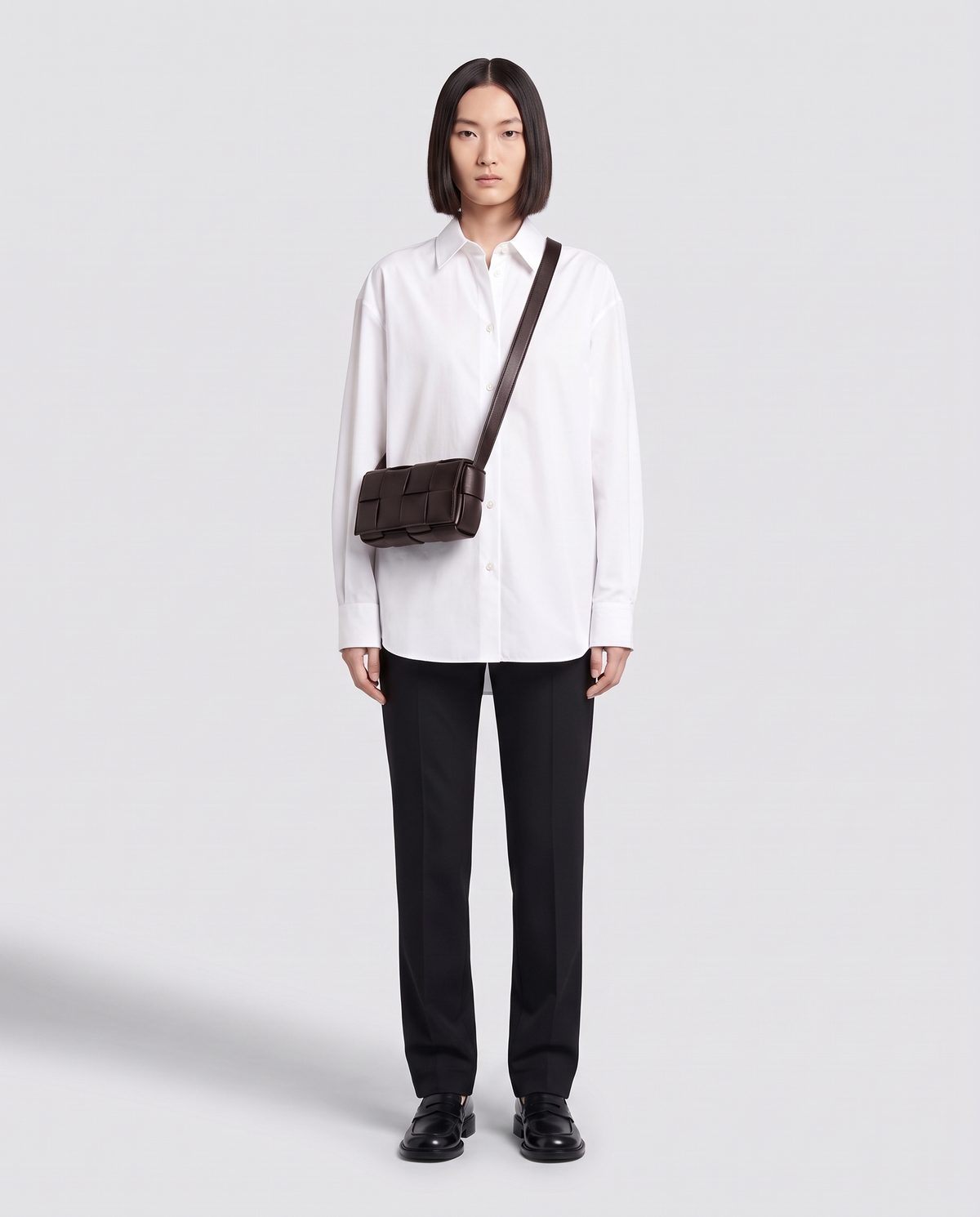 Cassette padded woven leather belt bag in Espresso – model wearing it crossbody, full length