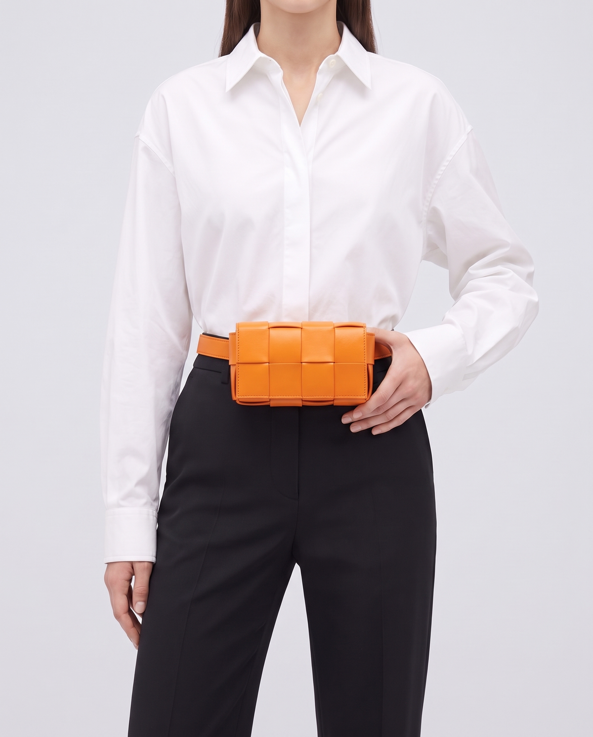 Cassette padded woven leather belt bag in Orange – model wearing it at the waist