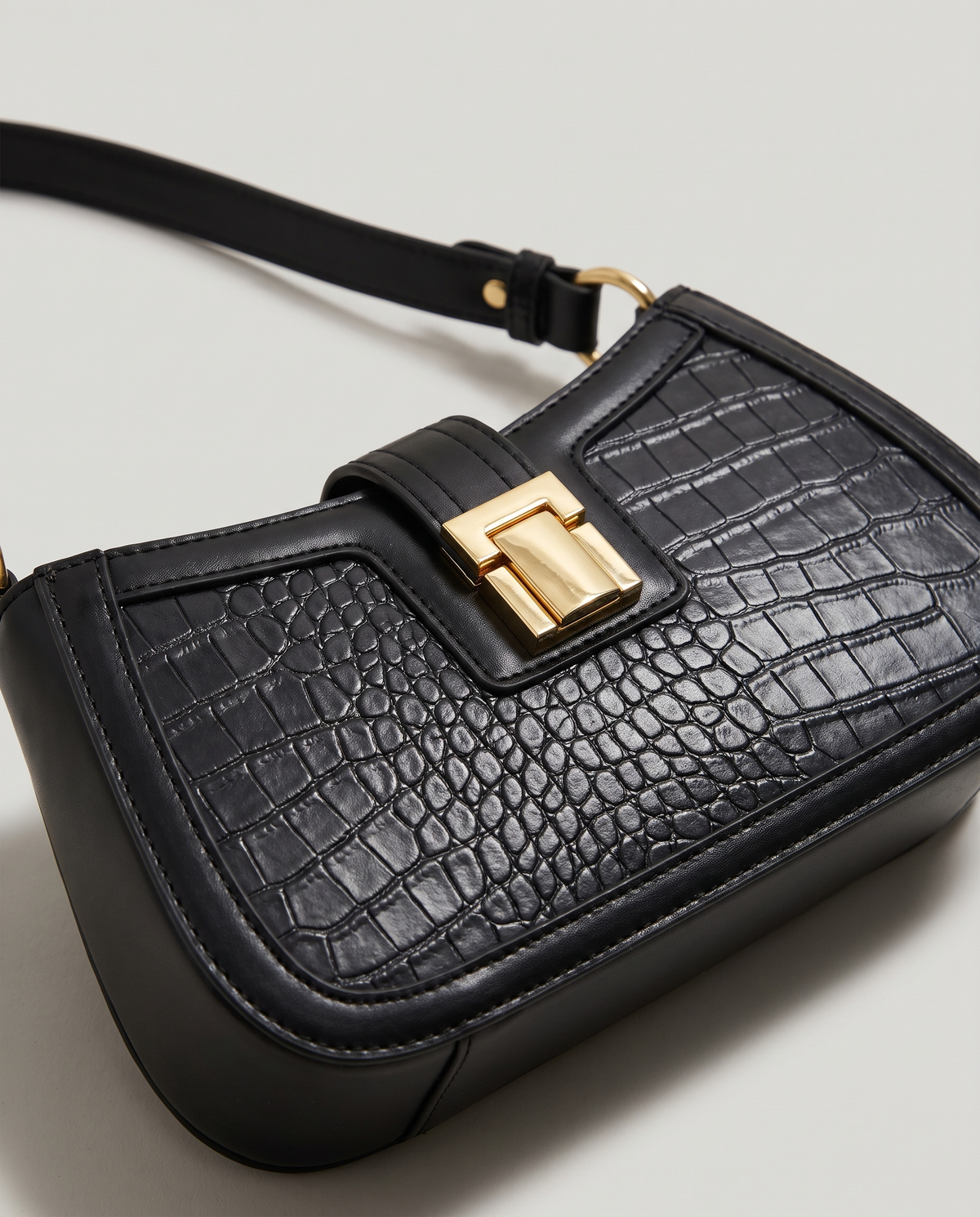 Sable croc-embossed shoulder bag in Black – close-up of the gold push-lock clasp