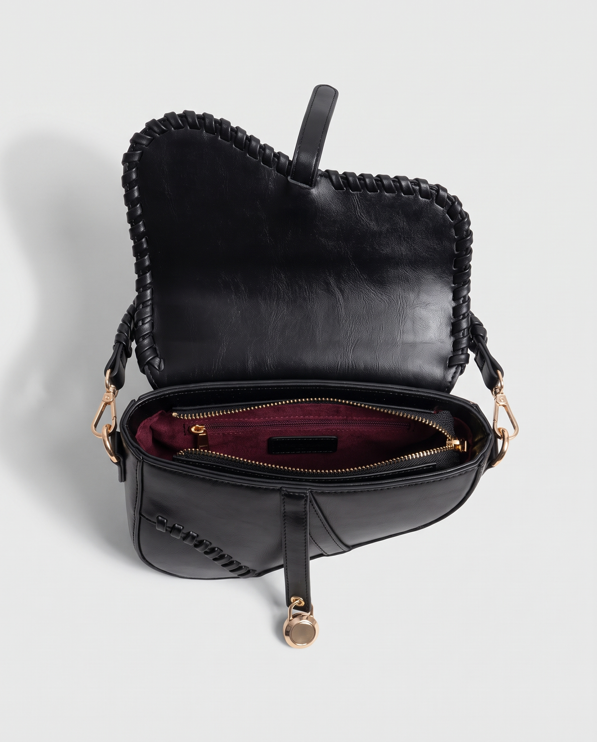 Saddle vegan leather shoulder bag in Black – open, showing the burgundy lining and zip pocket