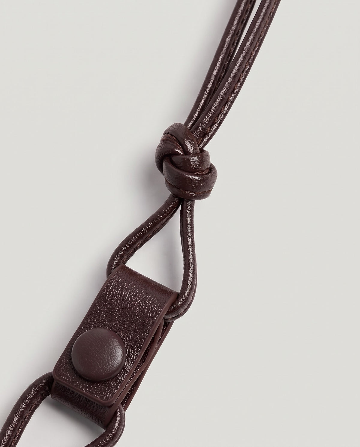 Serata woven leather clutch in Burgundy – strap knot and snap detail