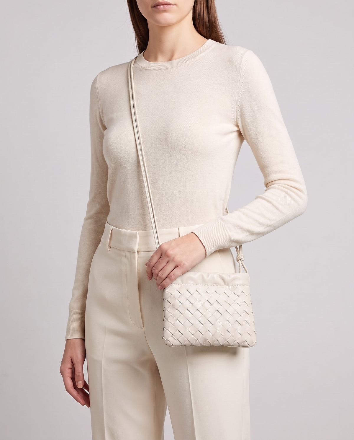 Model wearing the Serata woven leather clutch in Ivory crossbody