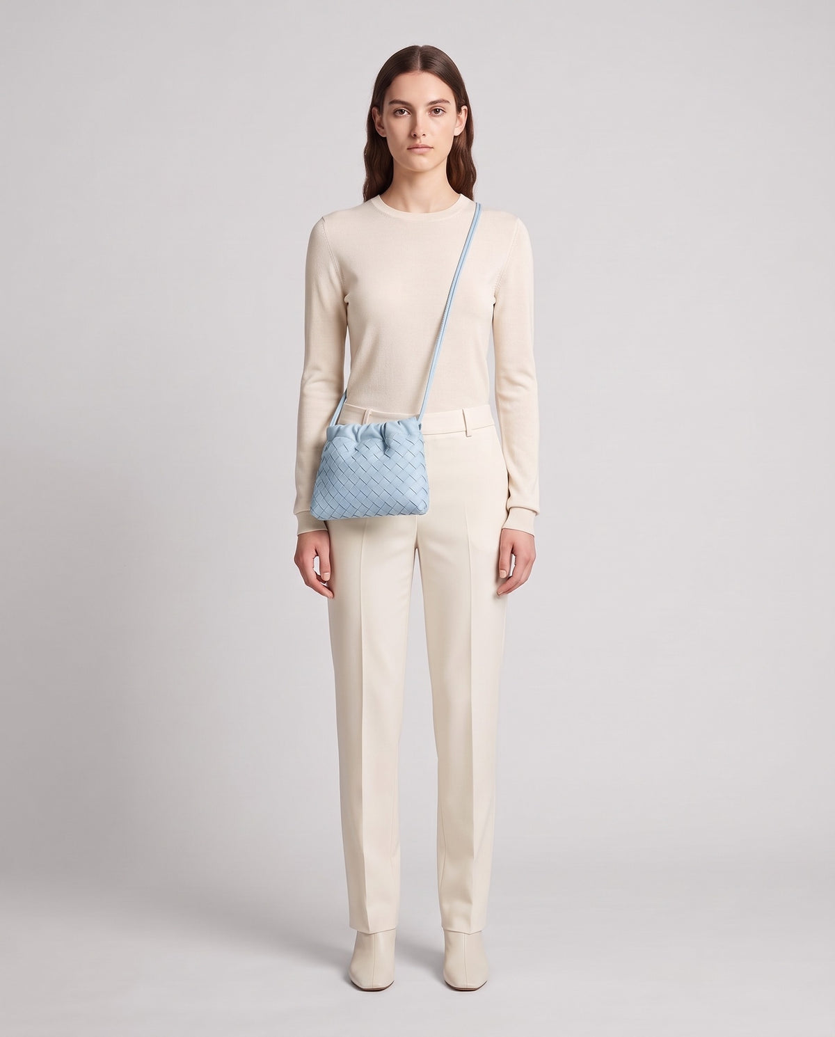 Model wearing the Serata woven leather clutch in Sky – full length