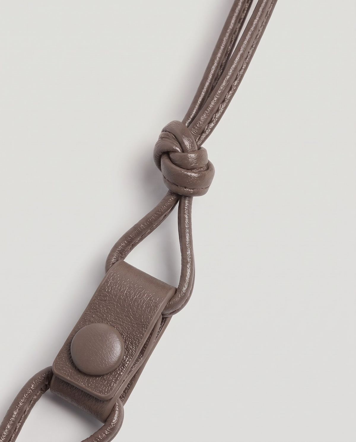 Serata woven leather clutch in Taupe – strap knot and snap detail