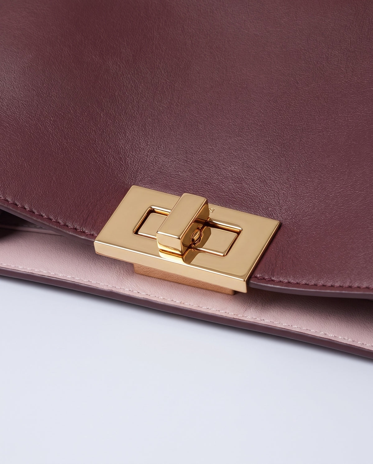 Siracusa leather bag in Burgundy – gold turn-lock clasp detail