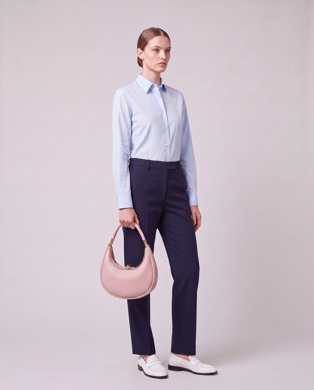 Model carrying the Todi crescent bag in Blush by the top handle – full-length view