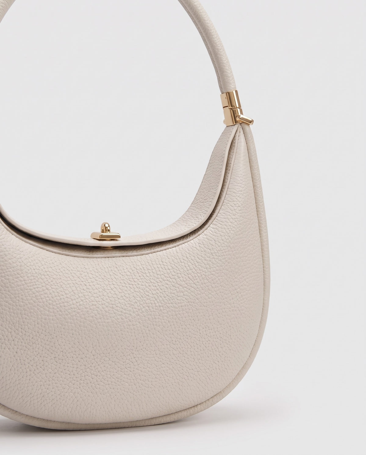 Gold clasp and handle collar detail on the Todi crescent bag in Ivory