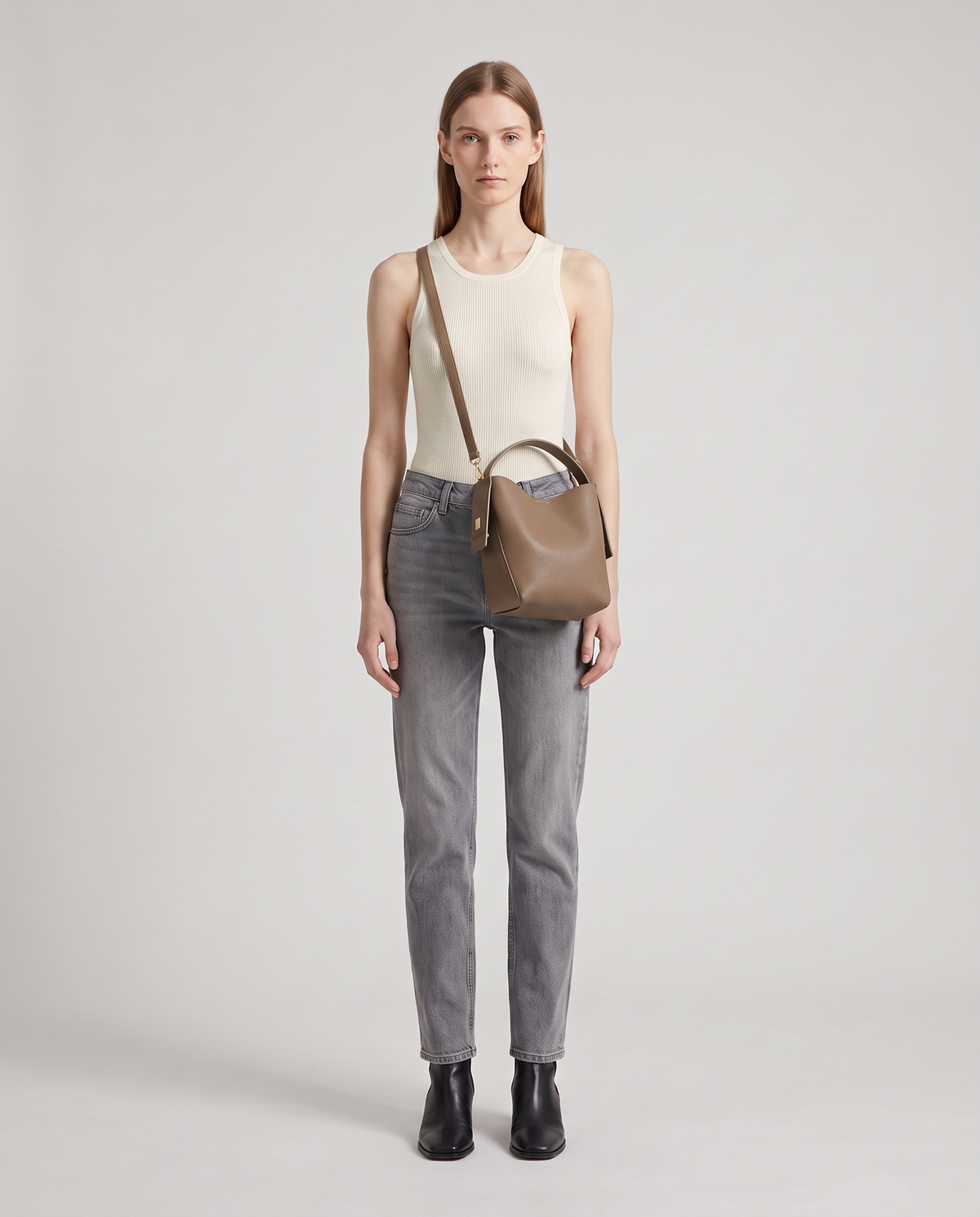 Transit leather bucket bag in Taupe – model wearing it crossbody, full length